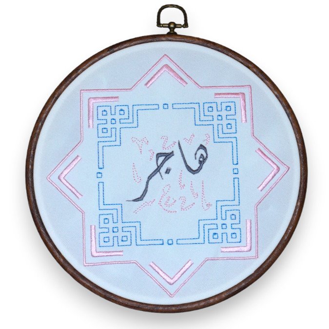 Embroidered geometric design with a central abstract figure in an embroidery hoop.